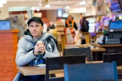 Man drinking coffee sitting in Cafe. Focus is on face. Shallow depth of field.